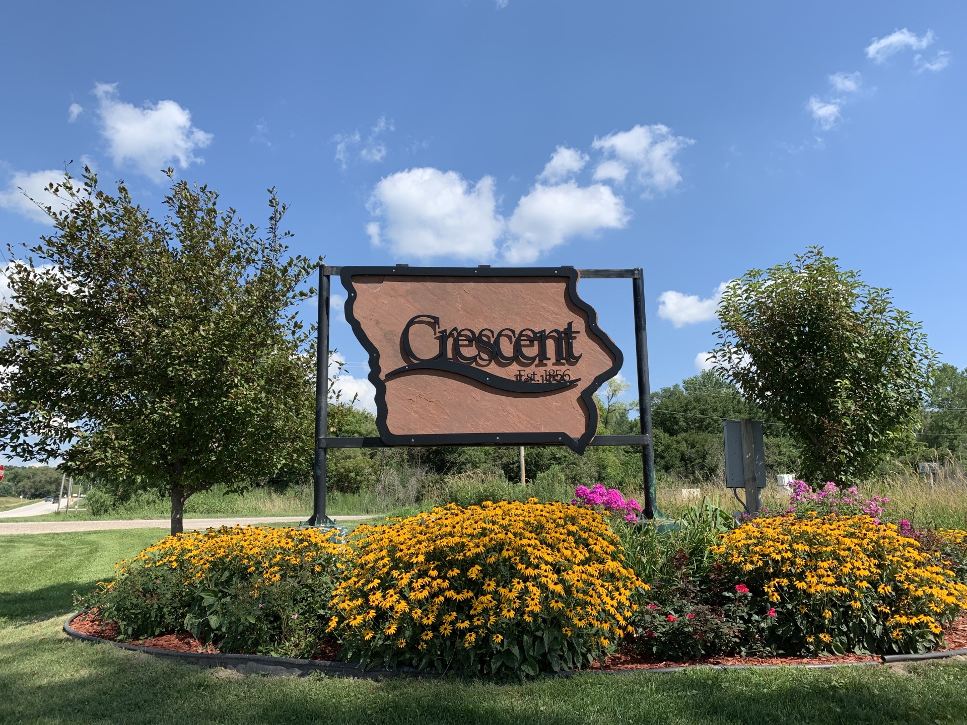 Crescent established 1856 sign, surrounded by yellow flowers.