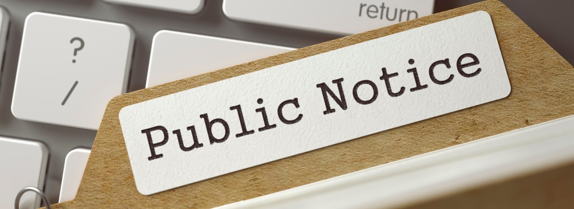Public notice text on a folder in front of a keyboard