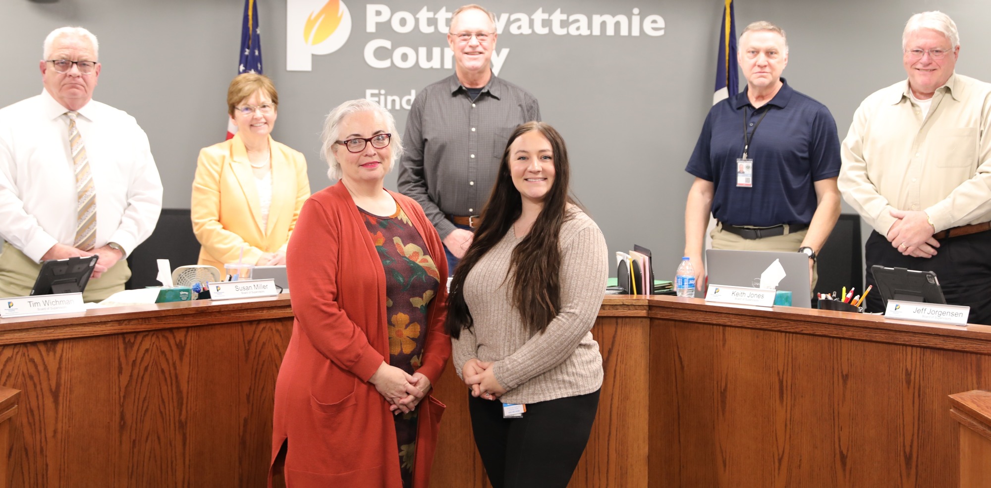 Board of Supervisors and Public Health representatives in front of Pottawattamie County logo