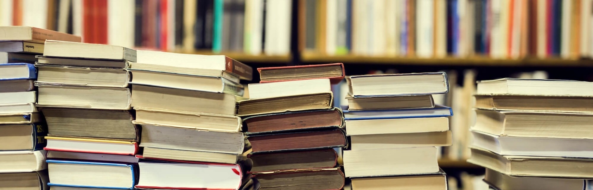 Stacks of library books in front of shelves of books