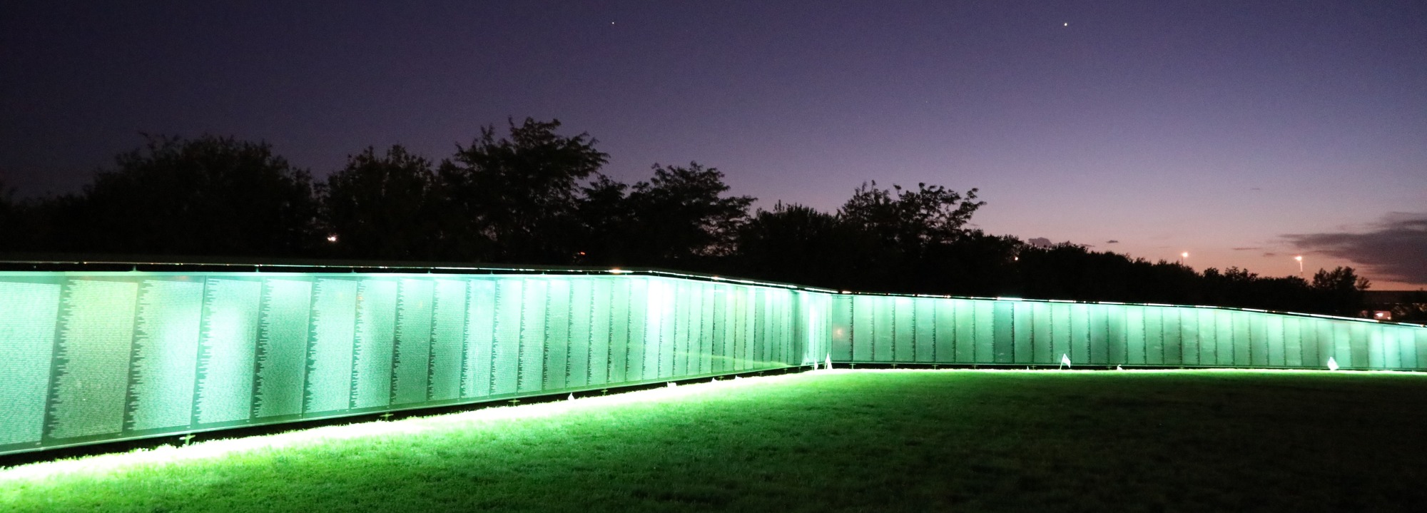 The Wall That Heals illuminated in teal after sunset
