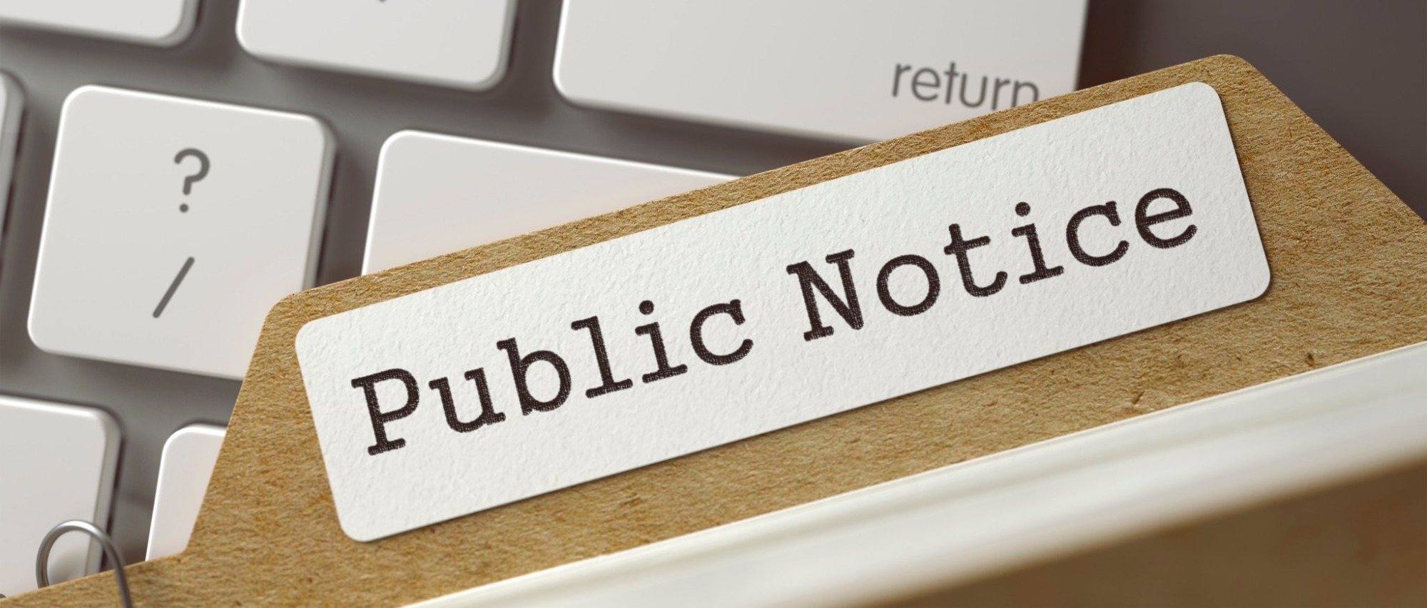 Public notice text on a folder in front of a keyboard