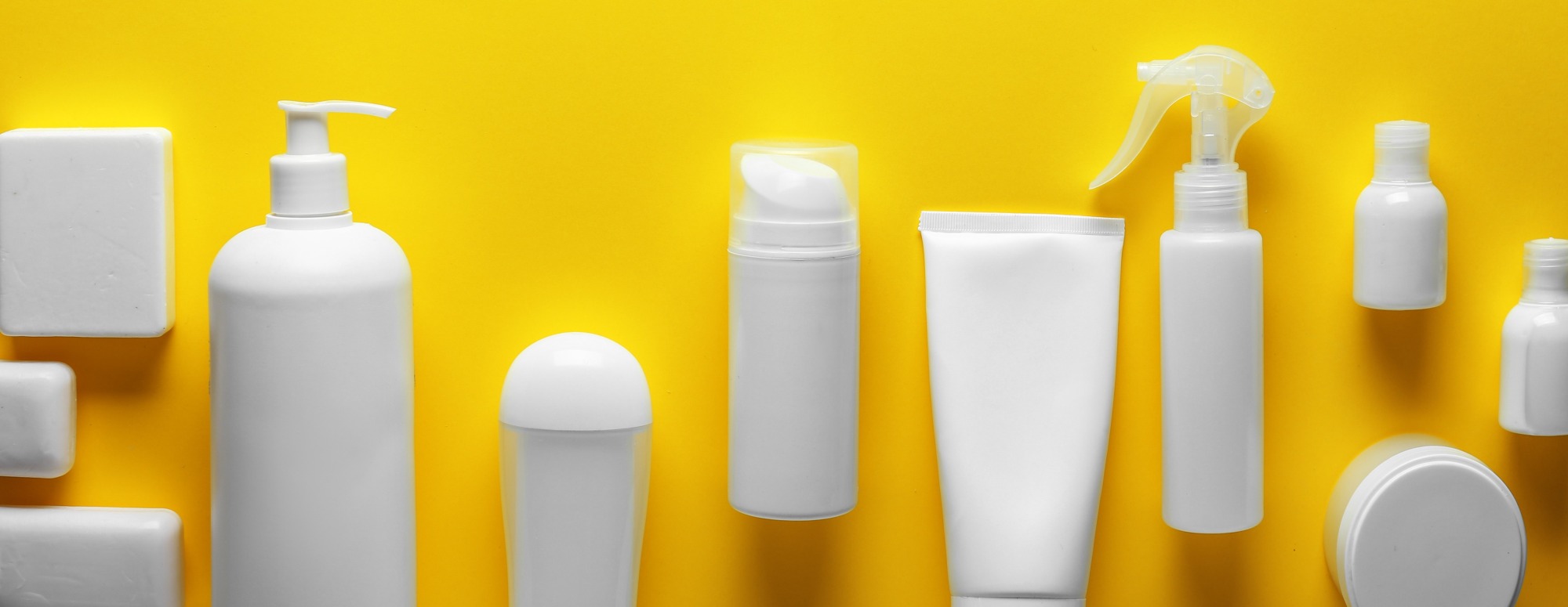 Unlabeled bottles of hygiene and personal care products on a yellow background